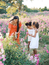 Expectant mom and her two daughters in the field picking flowers in Discovery Park