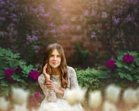 Child portrait in white lace dress surrounded by blooming flowers in a garden in New Bern North Carolina