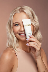 Paulina Michaels in a beauty shot holding a luxury skincare product, exuding elegance, captured by Ylva Erevall.