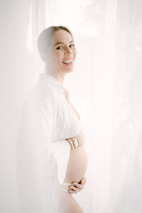 Pregnant woman in white open dress during studio maternity session Miami