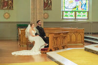 Bride and groom sitting during their wedding ceremony in a Los Angeles church with warm natural light and documentary style.