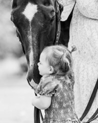young girl hugging her horse's face in a sweet embrace