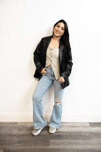Branding portrait of tattooed woman with long dark hair smiling while seated. Photograph by Yucaipa branding photographer Kaitlyn Dawn Photography.