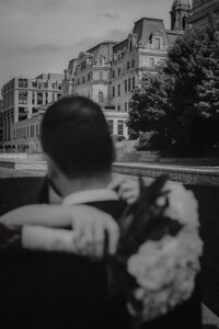 Couple de mariés enlacés, bouquet à la main, devant l’architecture historique du Vieux-Port de Montréal, capturé en noir et blanc — une image poétique et nostalgique signée par un photographe de mariage à Montréal, mettant en valeur la connexion et l’élégance urbaine du lieu.