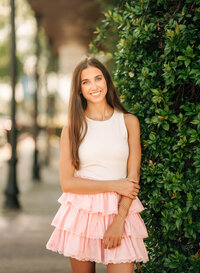 Senior portrait in downtown Foley, Alabama — waist-up near greenery, wearing a white top and
pink skirt.