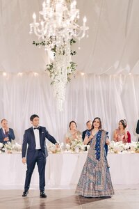 Couple performing a dance at a wedding reception with guests watching from the head table.