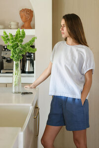 White textured linen top and blue shorts at a marble kitchen counter