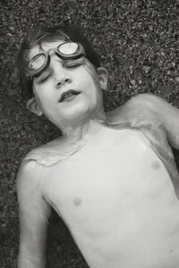 A young boy lays in the water in the backyard pool