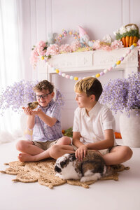 Siblings pet a live bunny and hold baby chics during Easter Mini Session at Holy City Babies Portrait Studio in Charleston, SC.