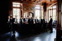 An editorial-style capture of a groom and his wedding party at a sophisticated bar, preserving the atmosphere of a multi-day celebration.