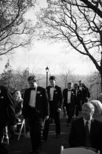 Black and white photo of the groomsmen walking down the aisle during the wedding ceremony at Burritt on the Mountain in Huntsville, Alabama, photographed by Perry Hancock.