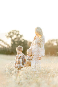 A mother standing in a Dallas/Fort Worth park with her two young boys standing close.