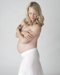Pregnant blonde woman embraces herself during maternity photography session