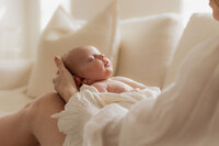 sleeping-newborn-cradled-cream-sofa-mom-blurred-in-home-boulder-photography-143