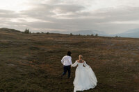 A couple runs through the hills of Bjorkliden in  Sweden after their wedding.