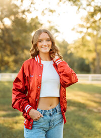 Senior portrait in downtown Magnolia Springs, Alabama — wearing her Saraland spartan letterman jacket with hand in pocket.
