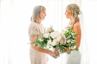 Wedding Photographer,  a bride stands with her mother as they hold a bouquet of flowers together