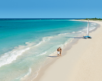 Traveler strolling along a secluded white sand beach with turquoise waves, symbolizing ultimate relaxation and getaway.