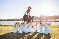 Bridal Party playful photoshoot where groom is thrown in the air at Loco Lake Event Venue captured by Graceful Ray Photography in Fort Worth Texas