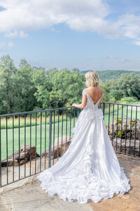bride at railing looking out into the rolling hills of Branson MO at Top of the Rock Chapel