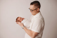 Newborn Photographer in Charleston -Father embraces his infant during Newborn Portrait Session in Charleston, SC.