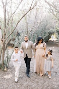 The Dilorio family walking hand in hand through a tree-lined path during a soft, natural light outdoor family photography session in Las Vegas.