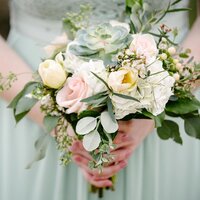 Close up of a bridesmaid in a sea green dress holding beachy floral bouquet