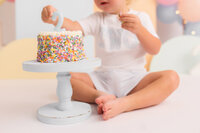 Toddler eats cake during his birthday Cake Smash Photoshoot at Holy City Babies Portrait Studio in Charleston, SC.