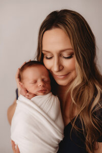 Newborn Photographer in Charleston - Mother embraces her infant during Newborn Portrait Session in Charleston, SC.