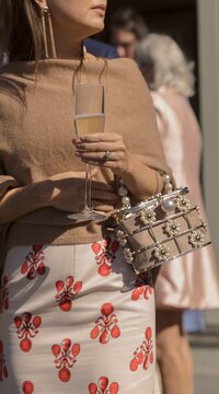 Guests holds a champagne flute with beaded bag and lobster dress.