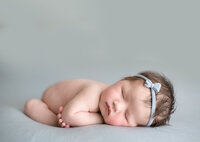 Newborn baby girl with headband  on light blue backdrop