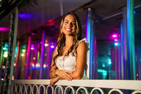 Senior portrait at the Greater Gulf State Fair in Mobile, Alabama — leaning on a railing in front of
a colorful funhouse.