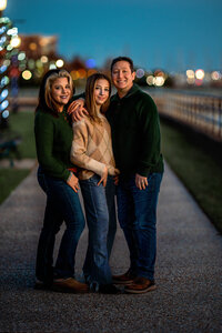 Parents standing with their teenage daughter on a downtown New Bern walkway at night