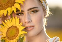 Confident high school senior in a sunflower field at sunset, her face softly lit by golden light during a senior in Green Cove Springs. (Photographed by Nature's Child Photography)