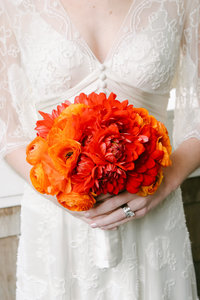 Bride detail with orange bouquet.