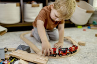 A young boy plays with a wooden train set at an in home session