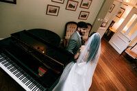 Candid wedding photography at tawstock court bride and groom sitting by piano together