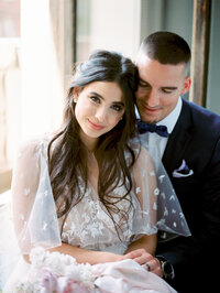 bride and groom sitting together laughing as she looks at the camera in a light and joyful moment