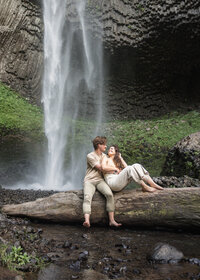 Couple sitting on log in front of latourell falls