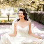 Bride in a strapless wedding gown sitting in the gardens of Hazlewood Castle, Yorkshire, captured by editorial wedding photographer.