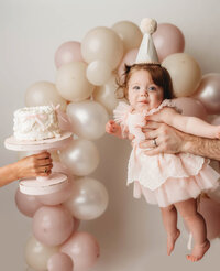 Charleston Cake Smash Photographer- Baby looks into the camera during Cake Smash Photos at Holy City Babies Portrait Studio in Charleston, SC.