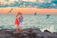 Siblings standing on rocks by the ocean in Eastern North Carolina