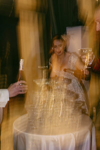 Artsy party photo of a champagne tower at a luxury wedding, captured with direct flash for a high-energy documentary feel.
