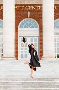Vanderbilt senior girl wearing robe and popping her heel in the air with cap high above