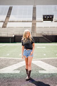 College senior wearing casual Vanderbilt shirt and skirt standing inside the campus football stadium
