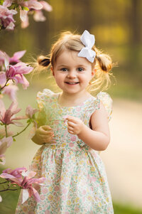 A little girl stands next to a magnolia tree in Oconomowoc while her portrait is taken by Kara Reese Photography.