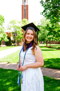 Senior girl standing on the grass at Belmont University with the campus bell tower behind her