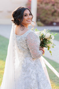 Bride looking back while holding bouquet