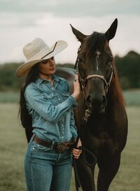 Senior portrait at Triple T Farms in Fruitdale, Alabama — standing beside her horse, petting his
cheek.