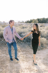 Parents from the Parker family holding hands and walking through the Las Vegas desert, captured in soft natural light during a romantic family photography session.